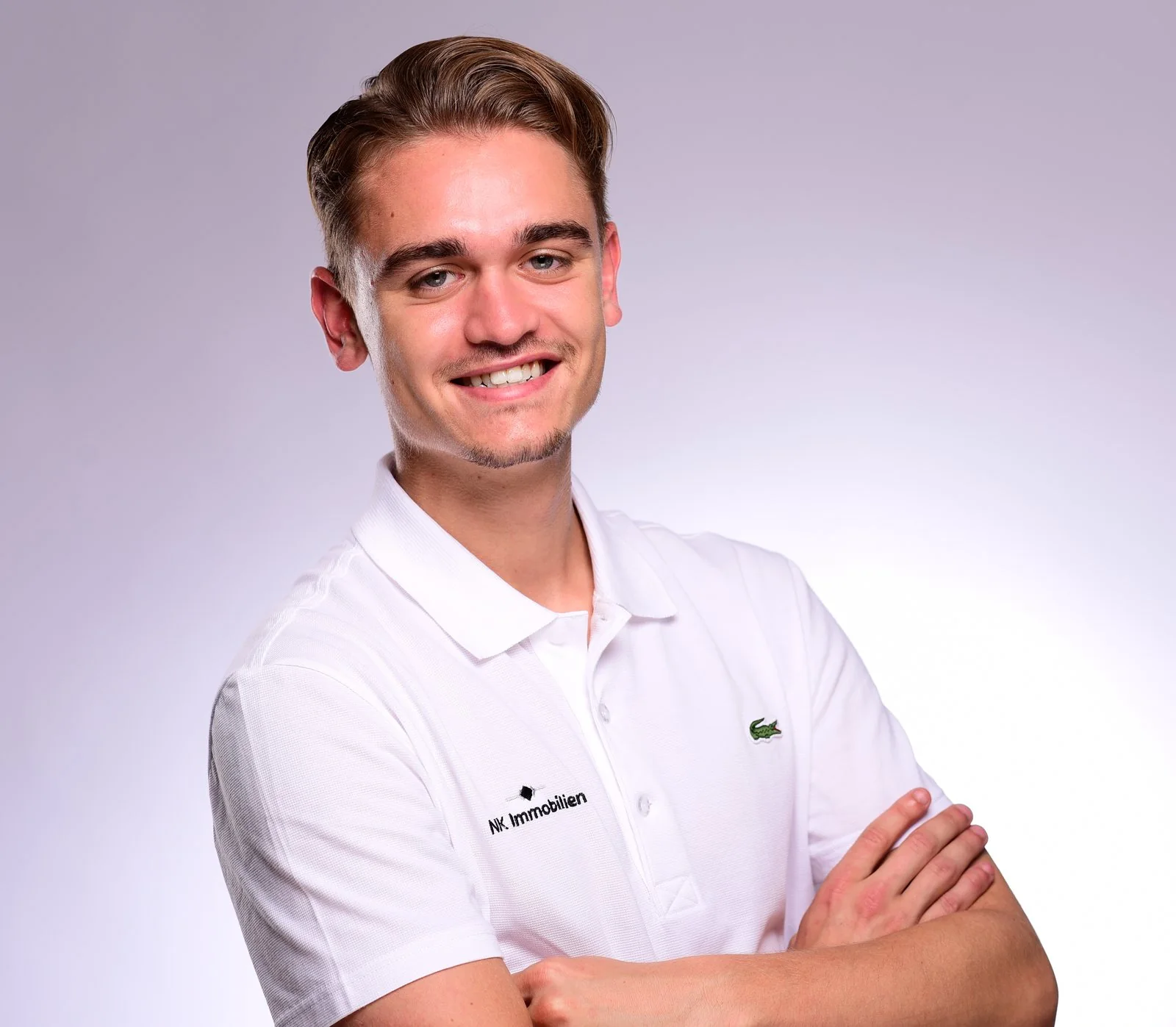 Niklas Kotte im weißen Poloshirt mit NK-Immobilien-Stickerei, Studioaufnahme